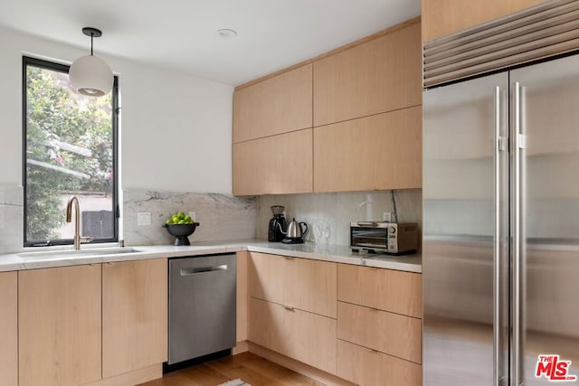 kitchen with pendant lighting, stainless steel appliances, sink, and light brown cabinets