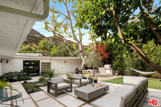 view of patio / terrace featuring exterior kitchen, a mountain view, grilling area, and an outdoor fire pit