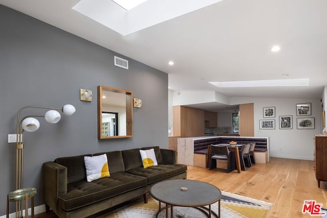 living room featuring light hardwood / wood-style flooring and a skylight