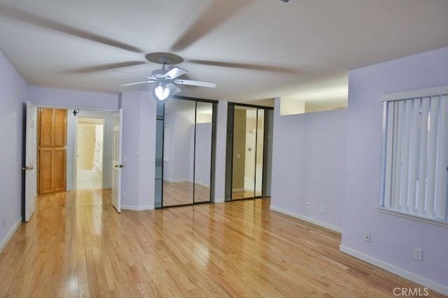 unfurnished bedroom featuring ceiling fan, two closets, and light wood-type flooring