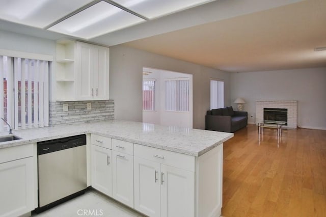 kitchen featuring white cabinetry, stainless steel dishwasher, kitchen peninsula, and light stone counters