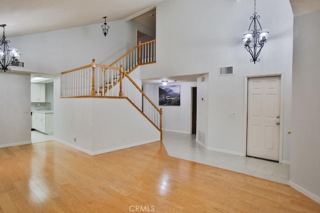 entryway featuring an inviting chandelier, high vaulted ceiling, and hardwood / wood-style flooring