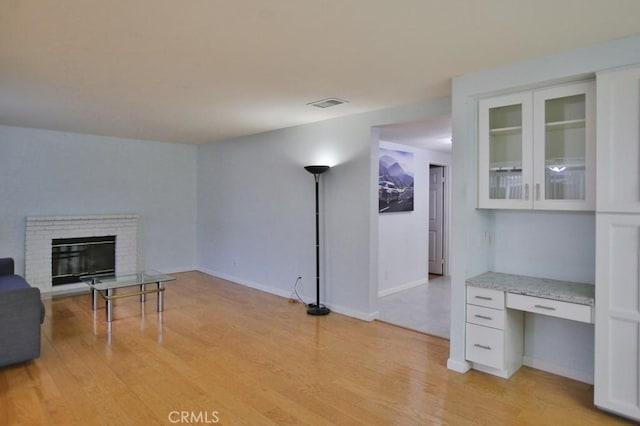 living room with built in desk, a fireplace, and light hardwood / wood-style flooring