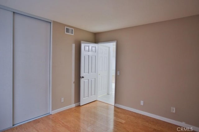 unfurnished bedroom with a closet and light wood-type flooring