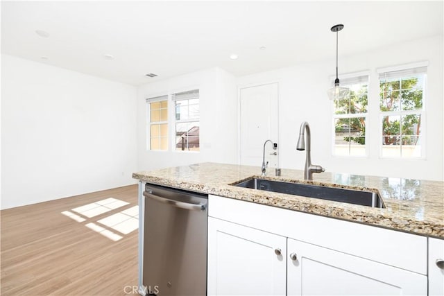 kitchen featuring sink, dishwasher, white cabinetry, hanging light fixtures, and light stone counters