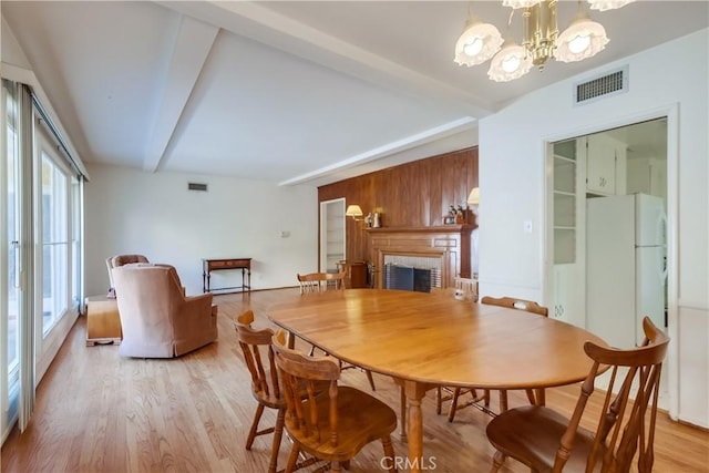 dining space with an inviting chandelier, beam ceiling, and light hardwood / wood-style floors