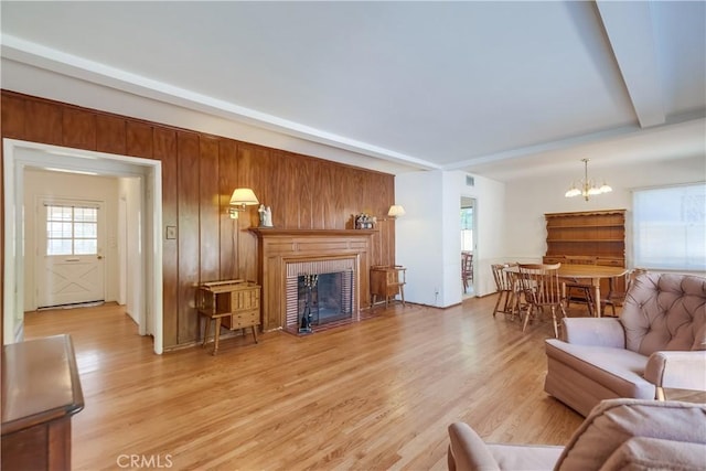 living room with wooden walls, a chandelier, and light wood-type flooring