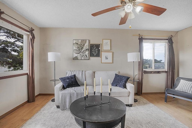 living room with ceiling fan, a textured ceiling, and light hardwood / wood-style floors