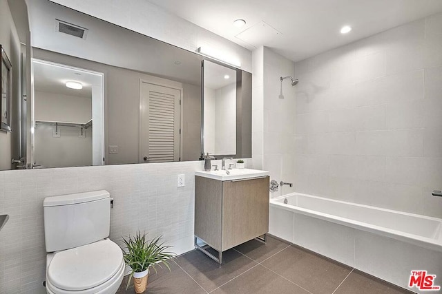 full bathroom featuring tile patterned flooring, tiled shower / bath, vanity, and toilet