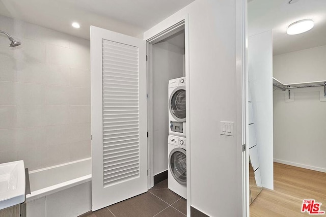 laundry room with hardwood / wood-style flooring and stacked washer / drying machine