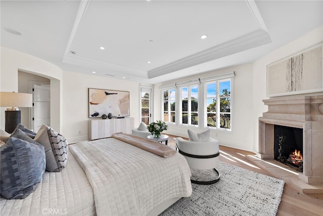 bedroom with crown molding, a raised ceiling, and light hardwood / wood-style flooring