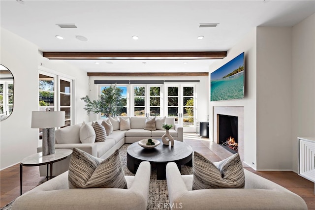 living room with beamed ceiling, a fireplace, and light hardwood / wood-style floors