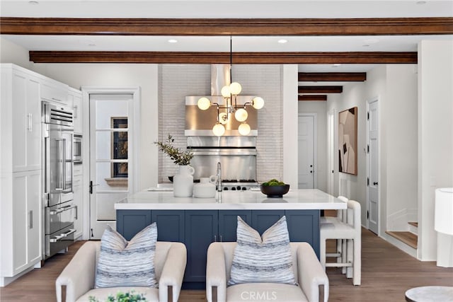 kitchen featuring blue cabinetry, a breakfast bar area, decorative light fixtures, beamed ceiling, and white cabinets