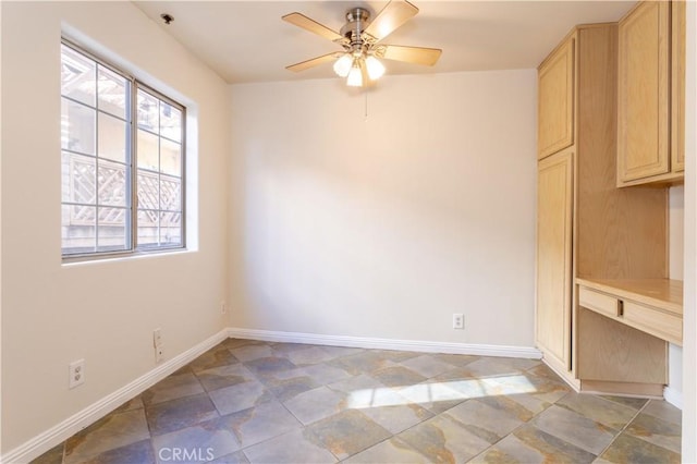 unfurnished room featuring built in desk and ceiling fan