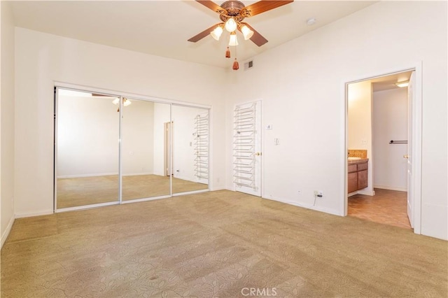 unfurnished bedroom with ceiling fan, carpet floors, ensuite bath, and a closet