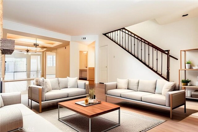 living room with a raised ceiling, hardwood / wood-style floors, and ceiling fan