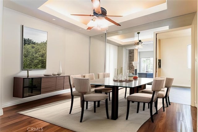 dining space featuring hardwood / wood-style floors, ceiling fan, and a tray ceiling