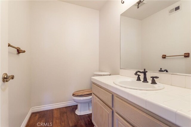 bathroom with wood-type flooring, vanity, and toilet