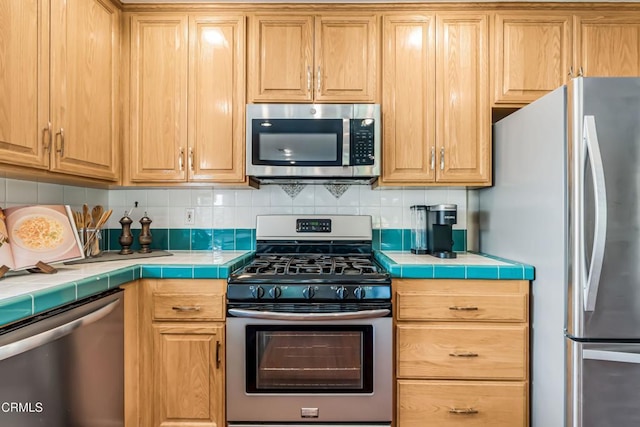 kitchen featuring decorative backsplash, tile counters, and stainless steel appliances