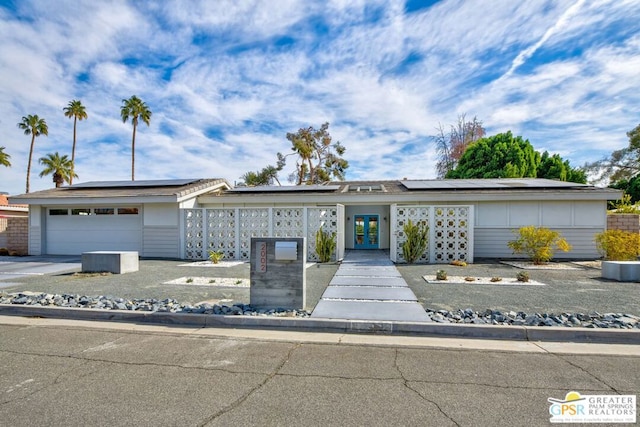 ranch-style house featuring a garage, french doors, and solar panels