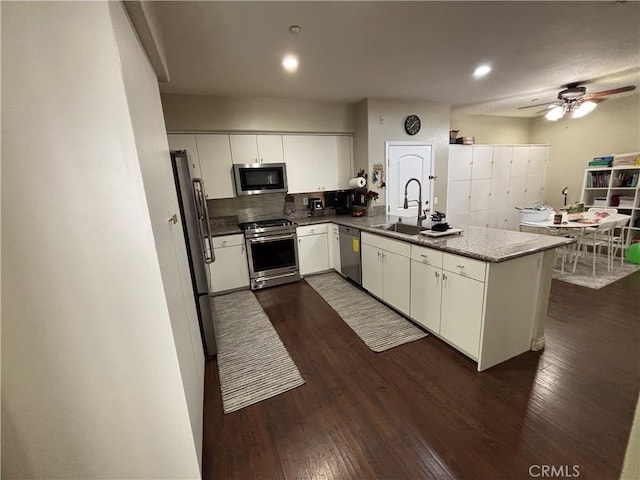 kitchen with sink, stainless steel appliances, dark hardwood / wood-style floors, white cabinets, and kitchen peninsula