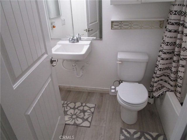 full bathroom featuring wood-type flooring, sink, shower / tub combo with curtain, and toilet