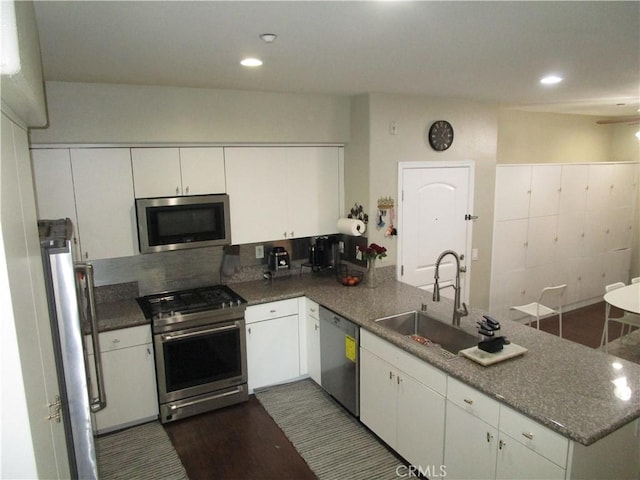 kitchen featuring sink, white cabinets, decorative backsplash, kitchen peninsula, and stainless steel appliances