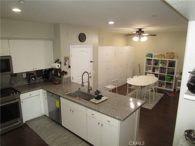 kitchen with white cabinetry, sink, stainless steel appliances, and kitchen peninsula