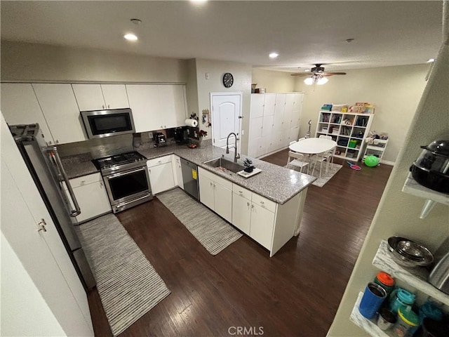 kitchen with appliances with stainless steel finishes, sink, white cabinets, and dark hardwood / wood-style floors