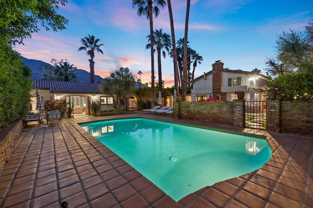 pool at dusk with a mountain view and a patio area