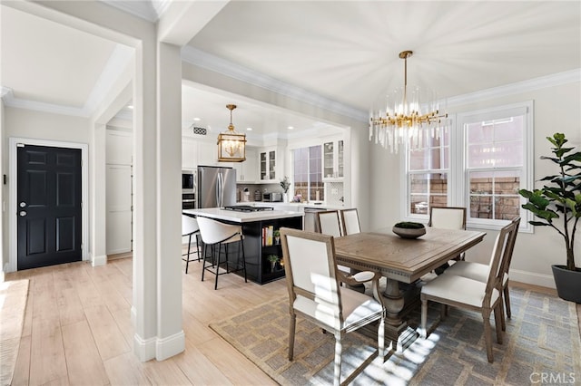 dining space featuring an inviting chandelier, crown molding, and light hardwood / wood-style floors