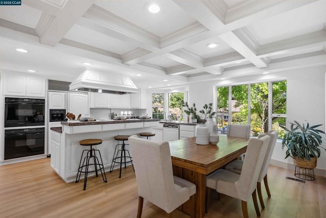 dining area featuring coffered ceiling, beam ceiling, and light hardwood / wood-style flooring