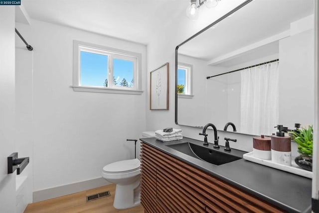 full bathroom with hardwood / wood-style flooring, vanity, toilet, and shower / tub combo