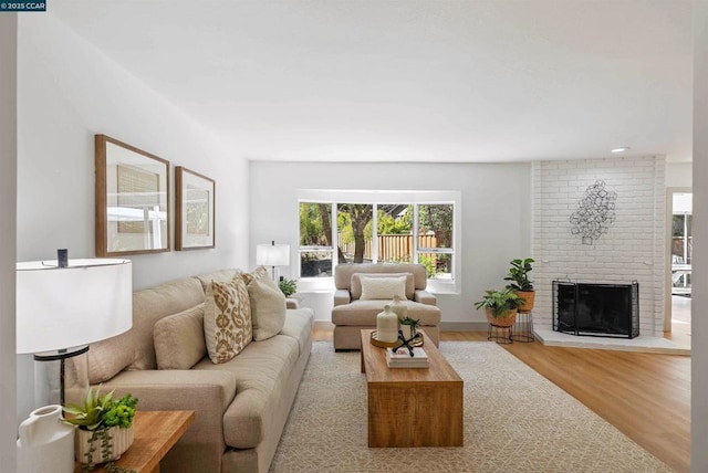 living room featuring a brick fireplace and hardwood / wood-style floors