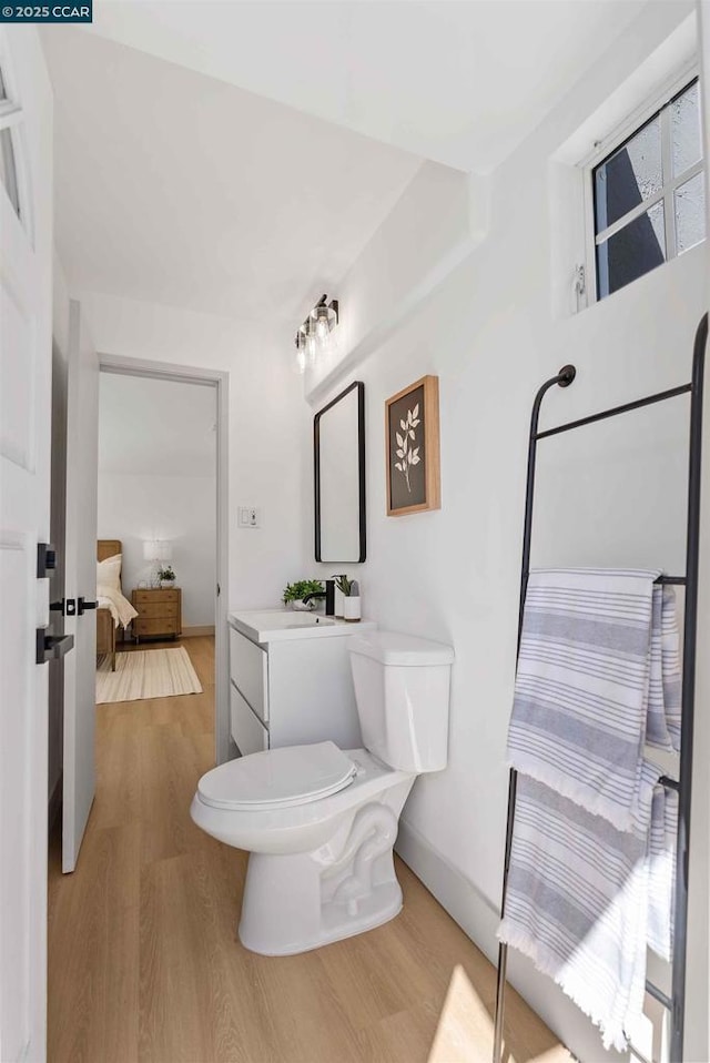 bathroom with wood-type flooring, vanity, and toilet