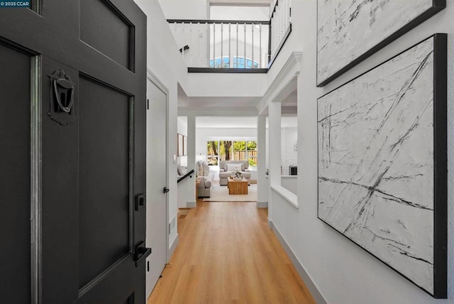 corridor with a high ceiling and light wood-type flooring