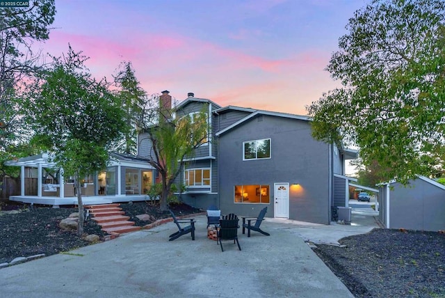 back house at dusk featuring a fire pit, a patio area, central air condition unit, and a pergola