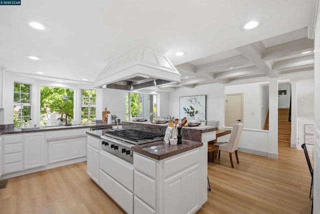 kitchen with sink, dark stone countertops, stainless steel gas cooktop, white cabinets, and custom exhaust hood