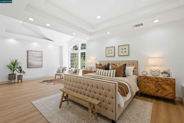 bedroom featuring a raised ceiling and light hardwood / wood-style flooring