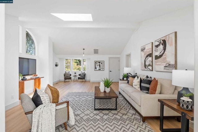 living room featuring beamed ceiling, a skylight, and light hardwood / wood-style flooring