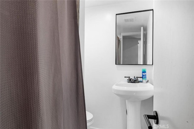 bathroom featuring a shower with curtain and toilet