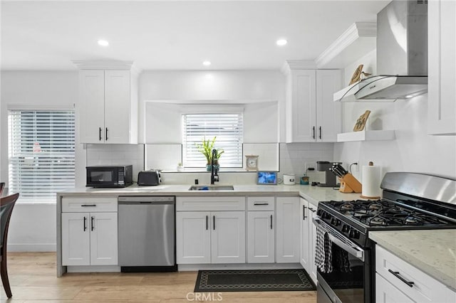 kitchen featuring white cabinets, stainless steel appliances, and wall chimney exhaust hood