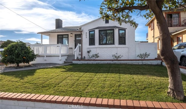 bungalow-style home featuring covered porch and a front lawn