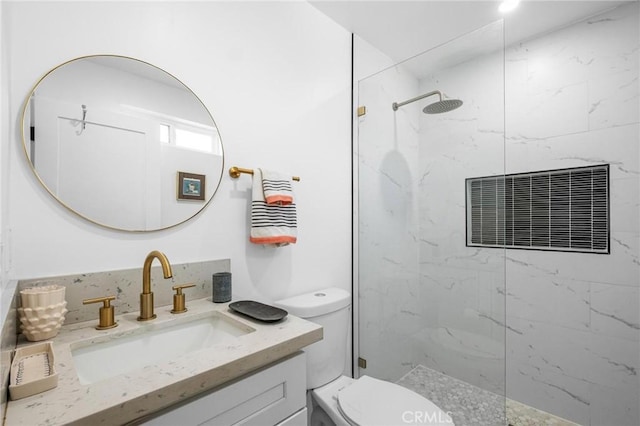 bathroom with vanity, toilet, and tiled shower