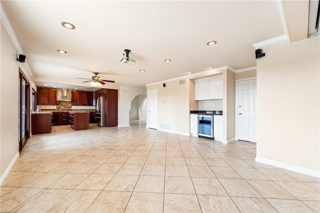 unfurnished living room with ornamental molding, light tile patterned floors, beverage cooler, and ceiling fan