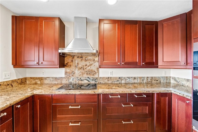 kitchen with wall chimney range hood, light stone counters, and black electric cooktop