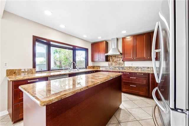 kitchen with sink, appliances with stainless steel finishes, a center island, light stone counters, and wall chimney exhaust hood