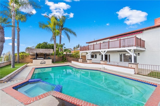 view of swimming pool with exterior bar and an in ground hot tub