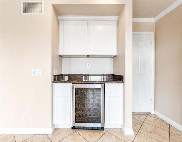 bar featuring wine cooler, ornamental molding, dark stone counters, and white cabinets