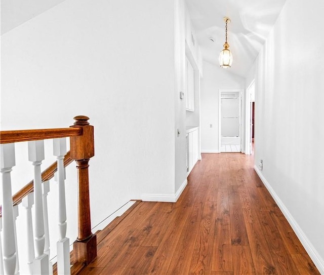 hall with vaulted ceiling and hardwood / wood-style floors